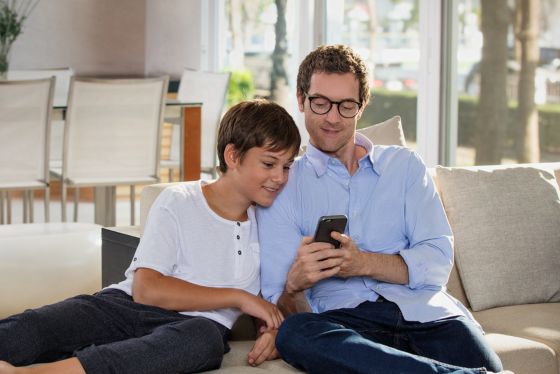 Vader en zoon gebruiken een smartphone met Varilux Digitime